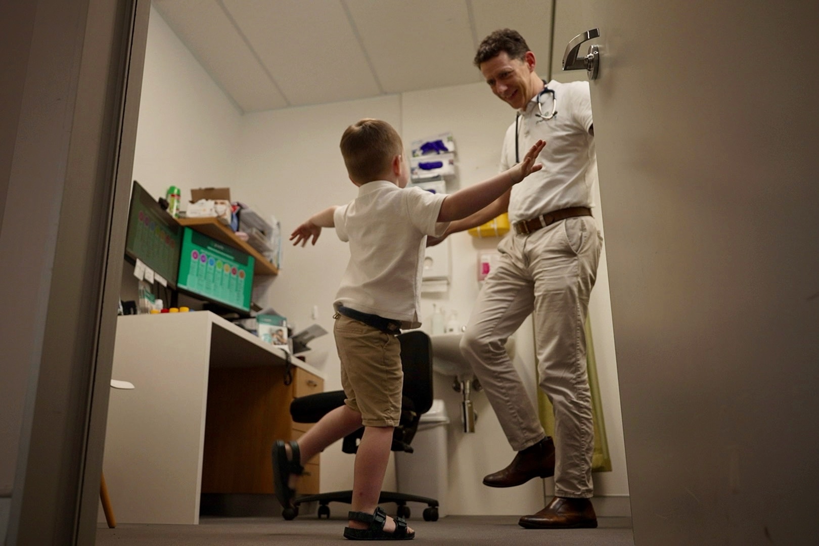 A doctor doing an activity with a three-year-old boy.