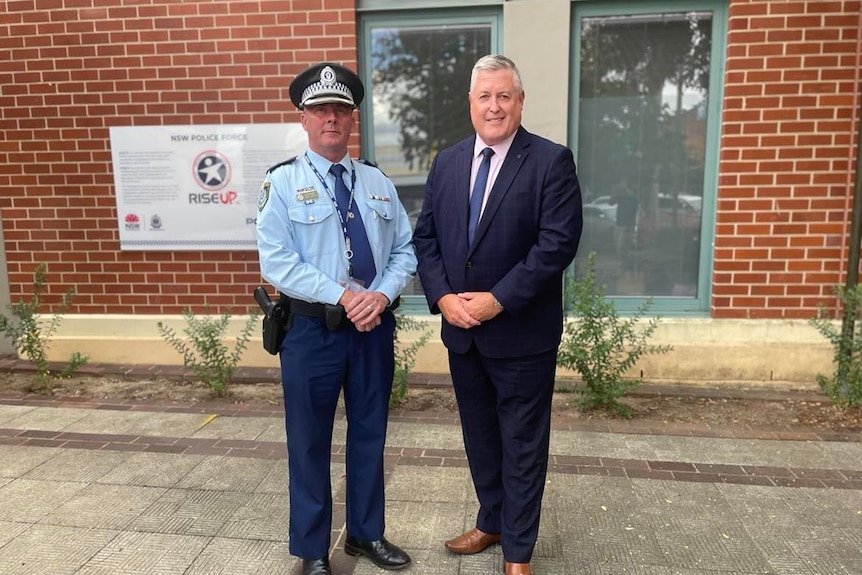 man in police uniform stands next to man in suit out front albury police station
