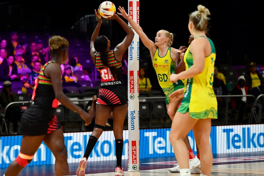 A Malawi goal shooter prepares to release thr ball toward the net as an Australian defender tries to block at Netball World Cup.