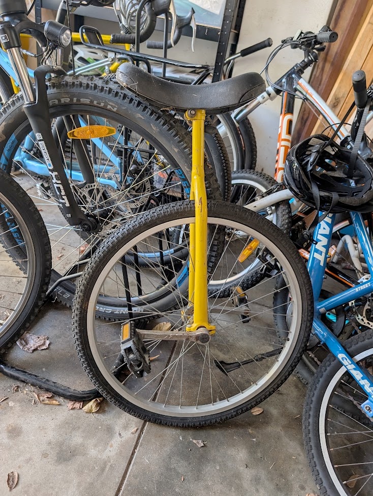 Image of a unicycle in a garage amongst bikes.