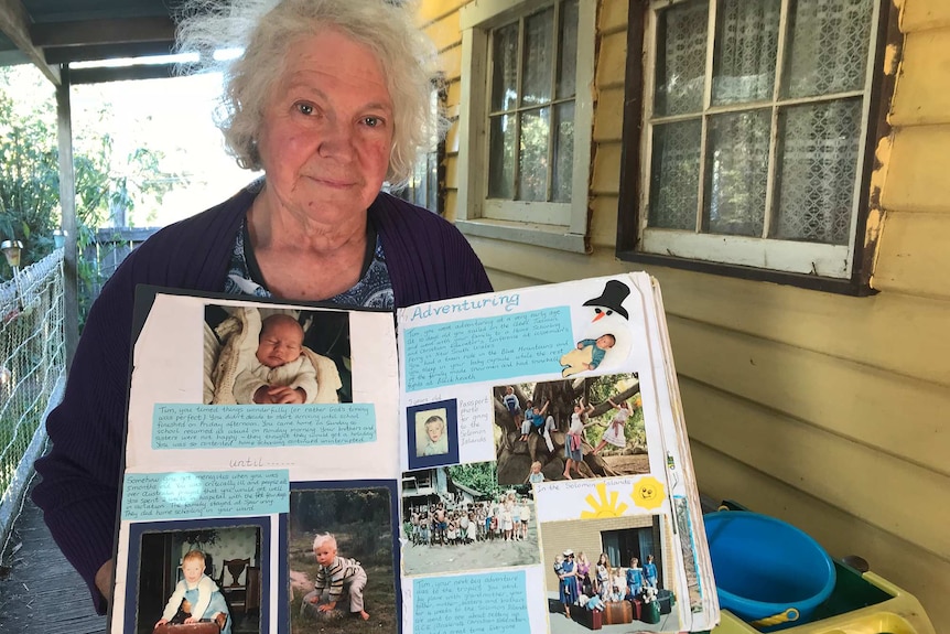 Beverley Rubenach holding a scrapbook of happy memories of her son Tim.