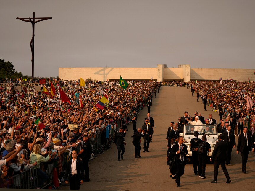 A sea of people on either sides of a walkway, raising and waving flags