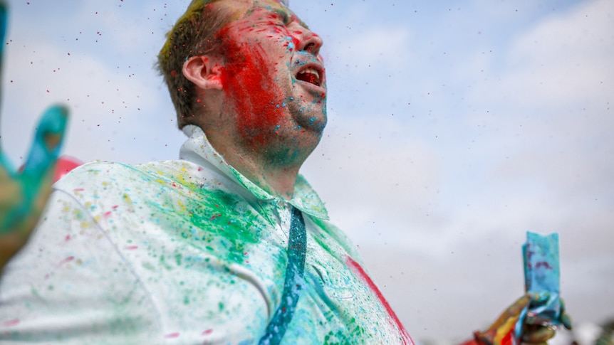 A man being sprayed with coloured powder