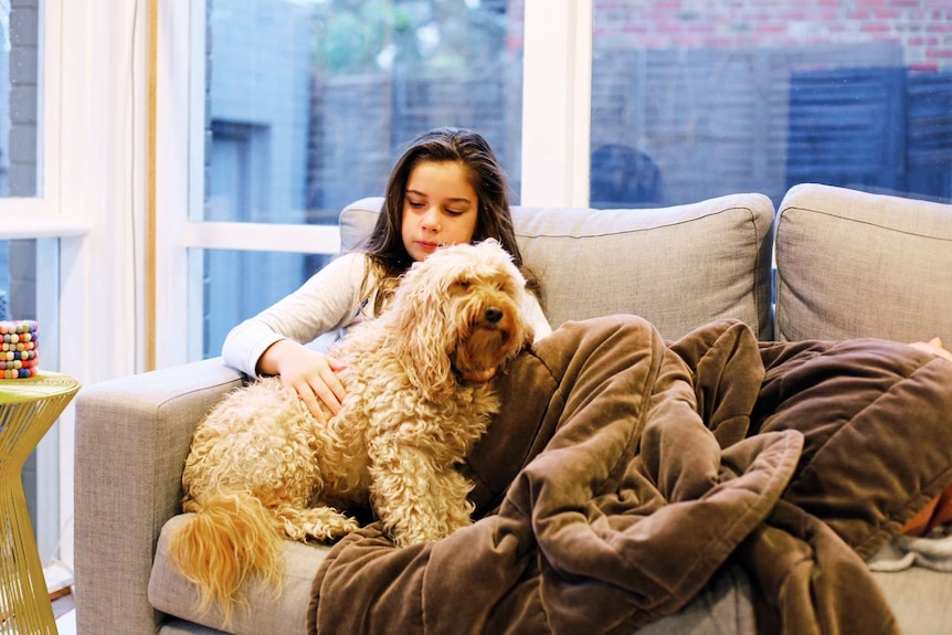 A young girl with a cream-colour dog sitting with her, illustrating the experience of being a child of someone with a disability