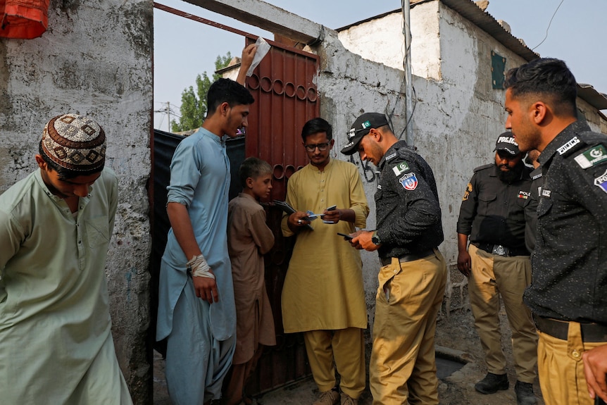 Police officers check the documents of a family outside their family home