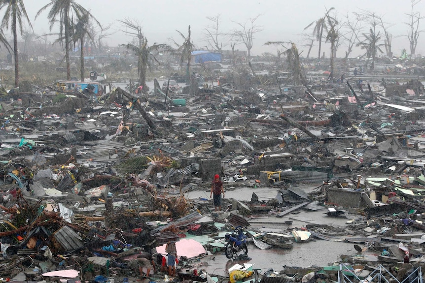 Survivors stand among debris and ruins of houses destroyed after Super Typhoon Haiyan battered Tacloban city.