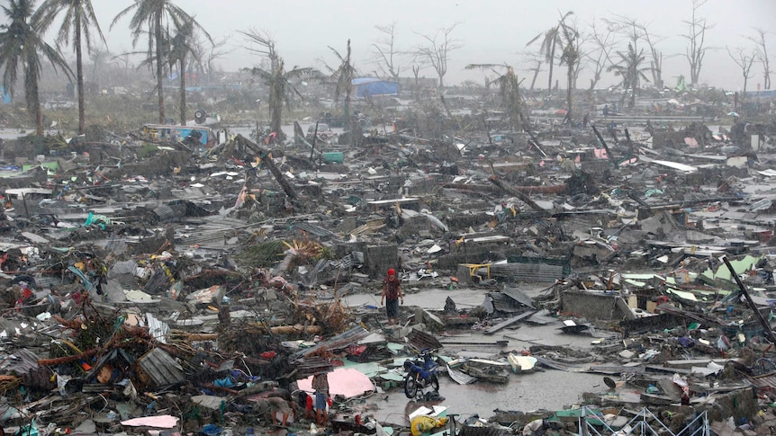 Survivors stand among debris and ruins of houses destroyed after Super Typhoon Haiyan battered Tacloban city.