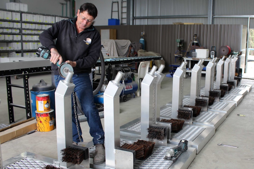 A photo of Rob Pernich working on some brush-down units in his workshop.