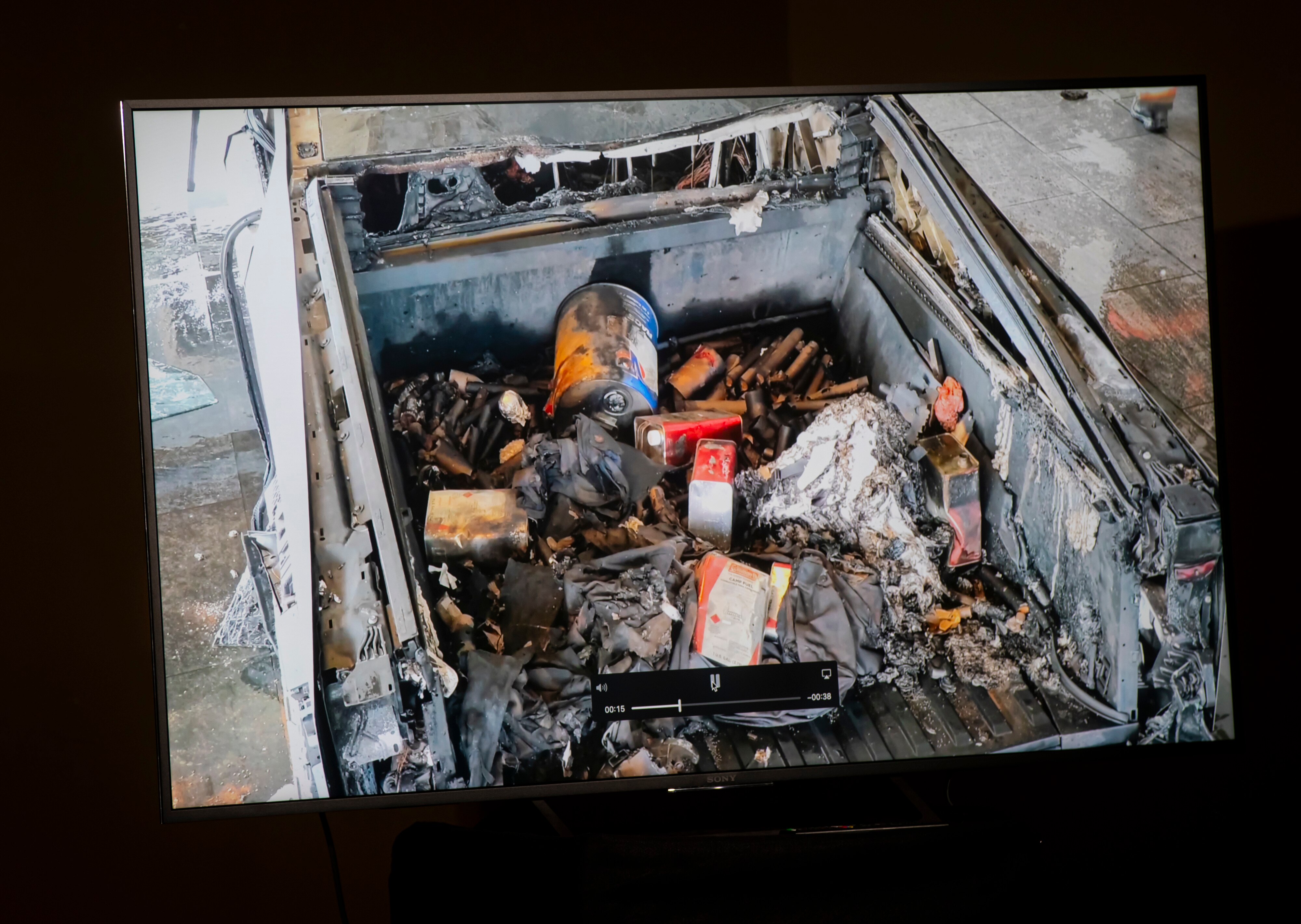 The burnt tray of a cybertruck contains fuel cans and other debris