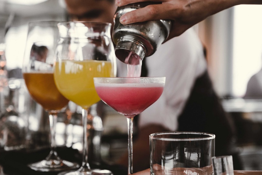 Someone pouring cocktails into glasses