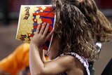 A young fan makes sure her popcorn is finished during a sporting event
