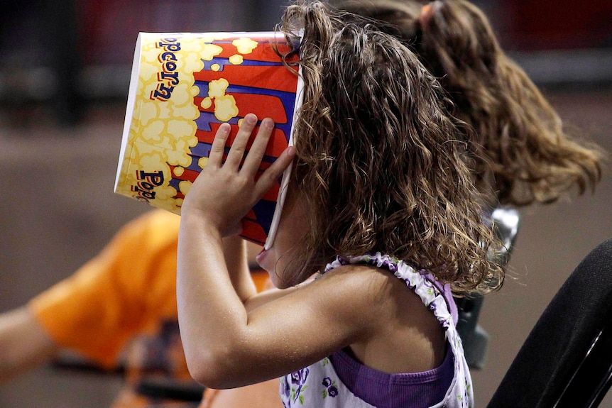 A young fan makes sure her popcorn is finished during an MLB National League baseball game.