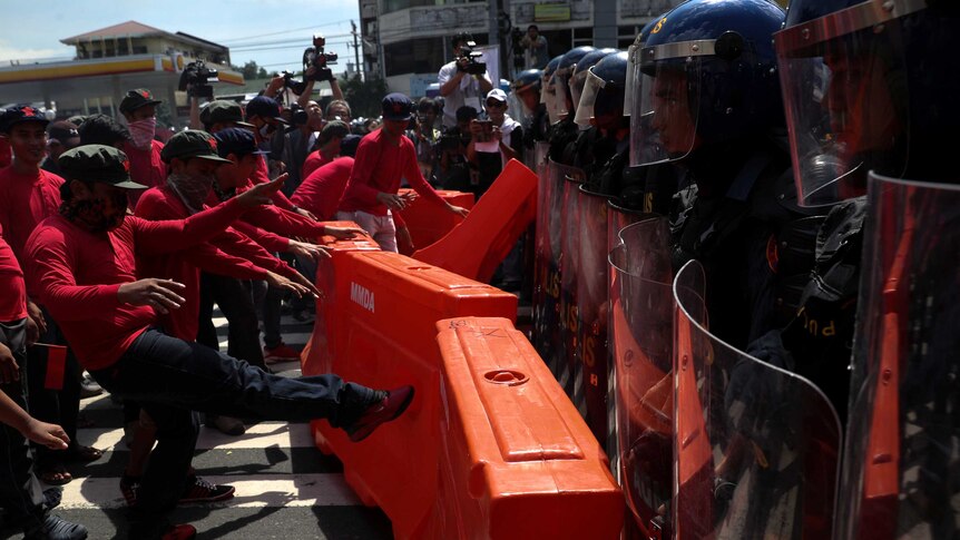 Protesters kick barricades towards anti-riot police officers.