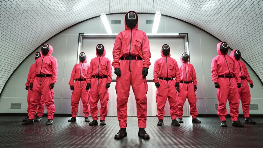 People wearing masks in bright pink jumpsuits