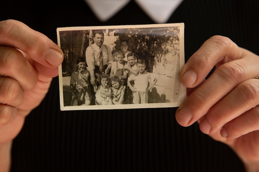 A woman's hands holding a black and white photo of a family