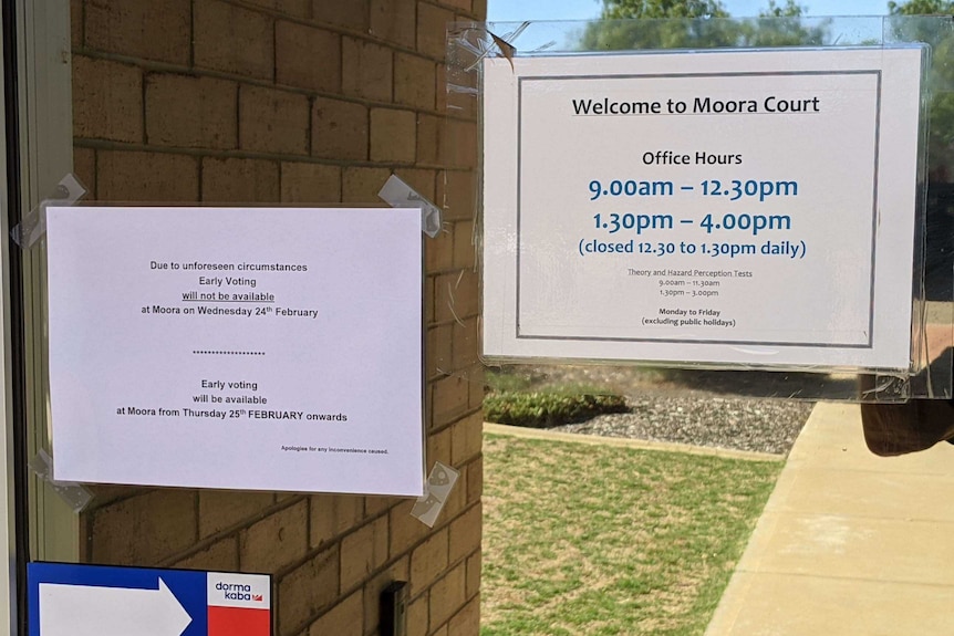 Two paper signs on a glass door, with one outlining opening hours and the other saying early voting will not be available.