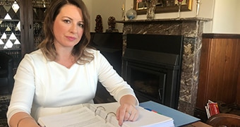 Kellie Tranter sits at a desk with documents in front of her.