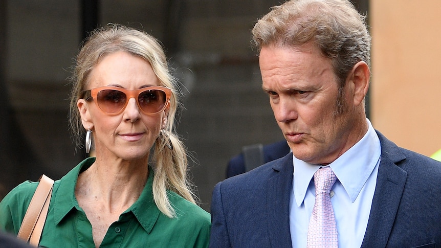 A man wearing a suit and a woman wearing a green dress and sunglasses