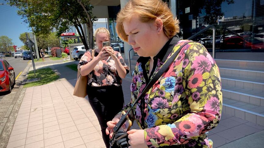 woman in floral shirt walking out of court
