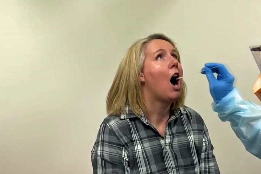 A long cotton swab is held near a woman's mouth