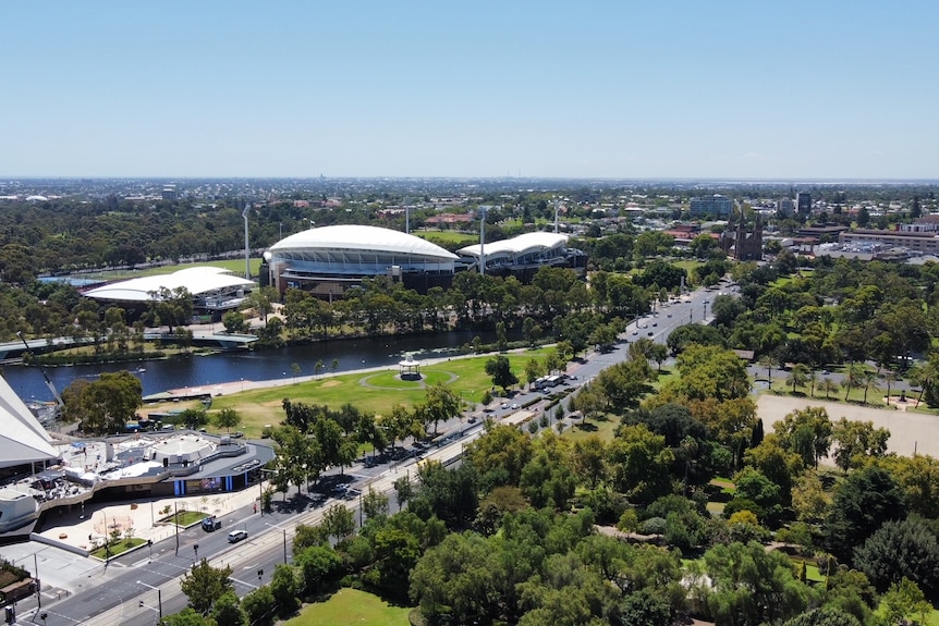 aerial view of a city street surrounded by greenery, buildings and a river running through