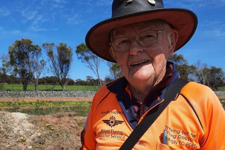 A woman wearing hi-vis and a hat with multiple badges smiles at the camera holding a business card