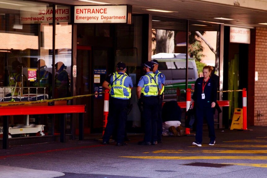 Police stand guard outside a hospital emergency entrance.