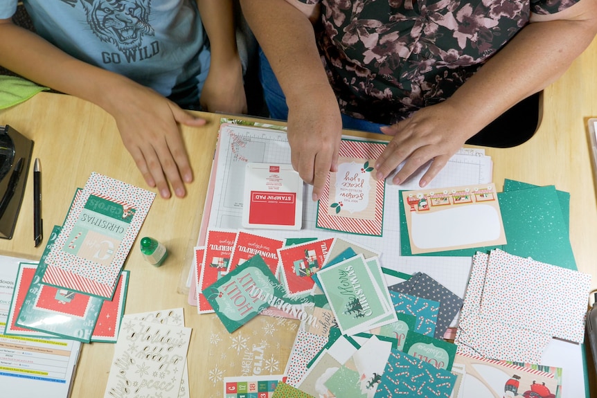 An overhead shot of hands sticking cards together, November 2022.