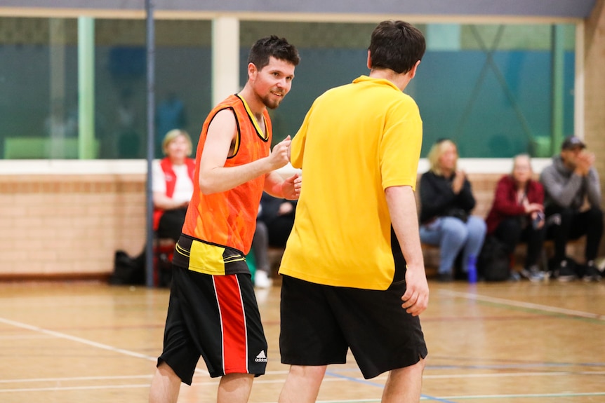 Two basketball players chat mid-game on court.