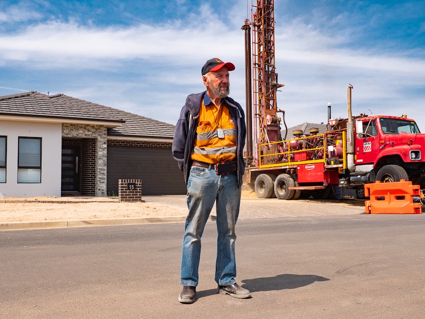 Man standing in front of house and bore drilling truck.