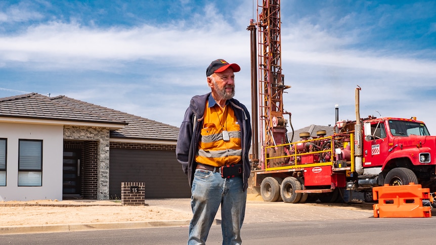 Man standing in front of house and bore drilling truck.