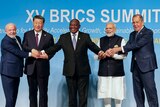 The leaders of Brazil, China, South Africa and India and Russia's foreign minister hold hands as they pose for a photo.