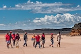 10 people walking across a salt lake on a sunny day.