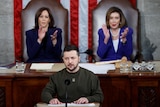 President Volodymyr Zelenskyy seated in front of two women at a microphone