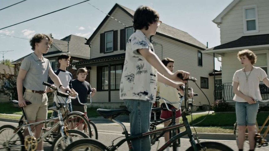 Still image from 2017 film IT of the protagonist group of Maine children on bicycles in a suburban setting.