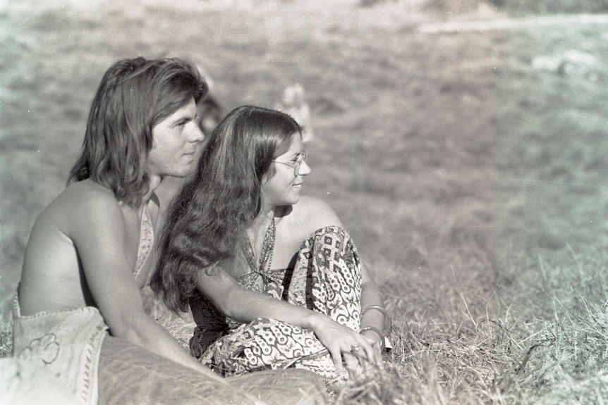 A black and white photo of a man and woman sitting outside on the grass