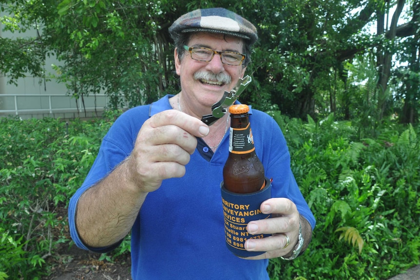 A man cracks a beer on a tropical backdrop.