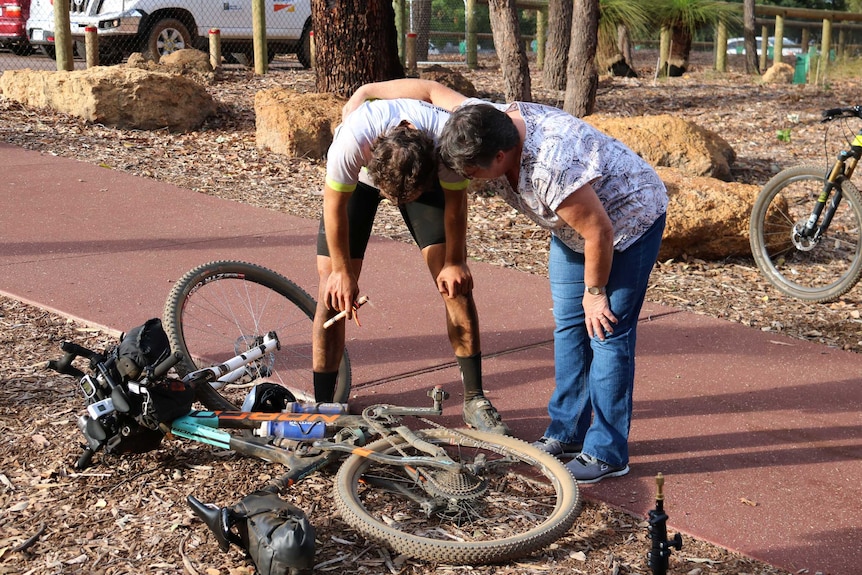 Declan von Dietze hunches over next to his mountain bike with his hands on his knees and his mum alongside him.