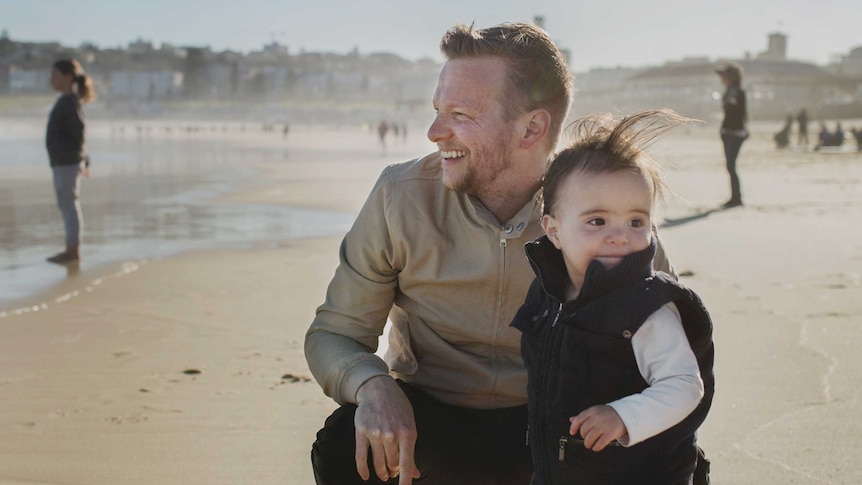 Sydney father Renn Holland and his child at the beach.