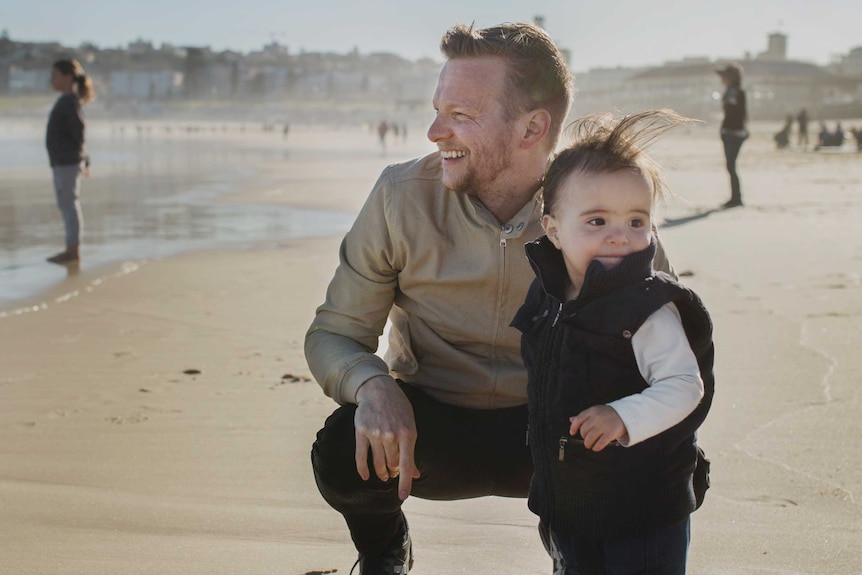 Sydney father Renn Holland and his child at the beach.