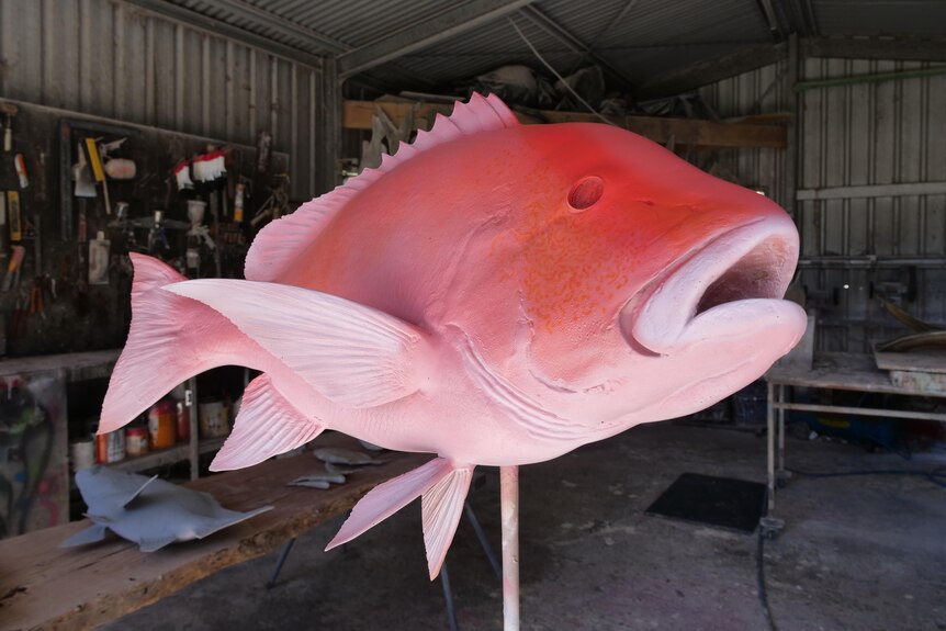 Un moule rouge d'un poisson sur un stand à l'intérieur d'un hangar.