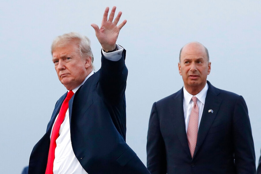 Donald Trump and Gordon Sondland are pictured against an overcast sky as the president waves to cameras with one hand.
