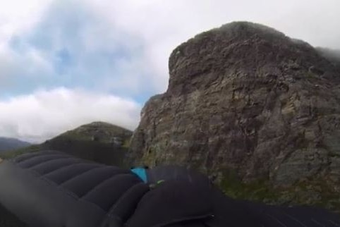 Black wingsuit extends out in front of Bluff Knoll peak
