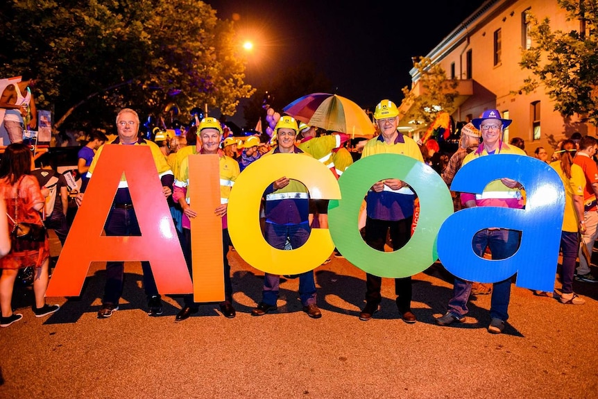 Five men stand holding rainbow letters