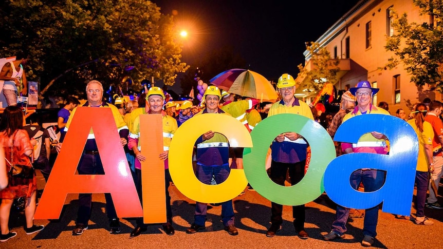 Five men stand holding rainbow letters