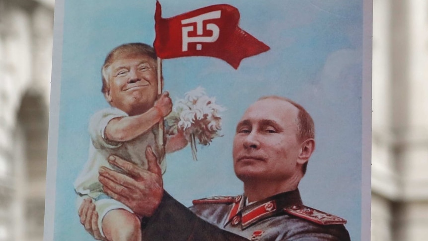 Man holds poster of Putin holding up a baby Trump.
