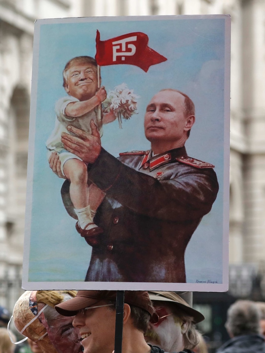Man holds poster of Putin holding up a baby Trump.