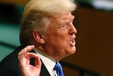 Donald Trump makes a hand gesture while giving a speech