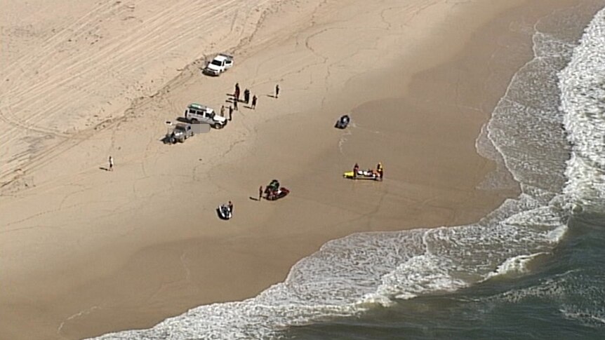 Authorities and other people on jet skis gathered on a South Stradbroke Island beach.