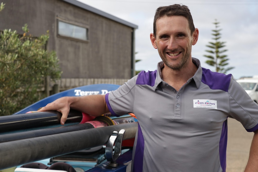 a man smiles while looking at the camera leaning against the boat